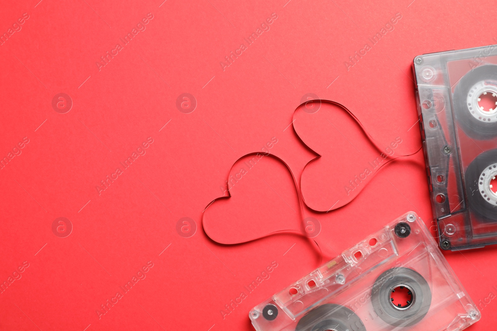 Music cassettes and hearts made of tape on red background, flat lay with space for text. Listening love songs Photo of Music cassettes and hearts made of tape on red background, flat lay with space for text. Listening love songs