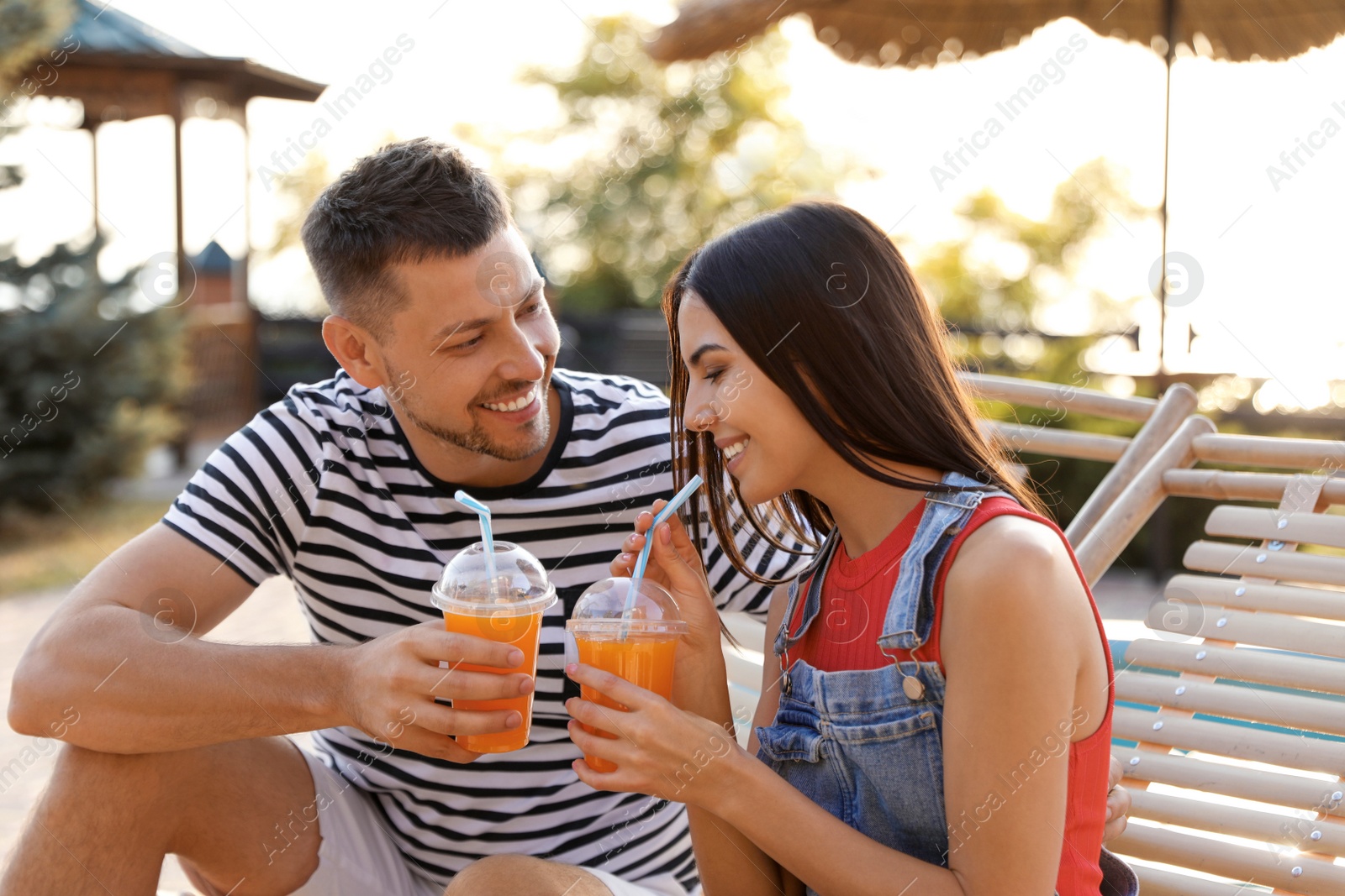 Happy couple with cups of refreshing drink resting in deck chairs outdoors Image of Happy couple with cups of refreshing drink resting in deck chairs outdoors