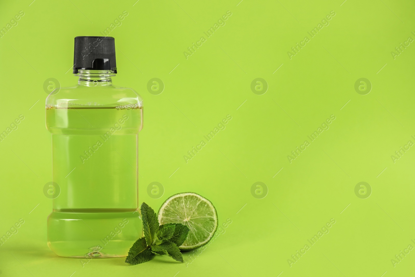 Mouthwash, fresh mint and lime on light green background. Space for text Photo of Mouthwash, fresh mint and lime on light green background. Space for text