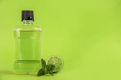 Mouthwash, fresh mint and lime on light green background. Space for text Photo of Mouthwash, fresh mint and lime on light green background. Space for text