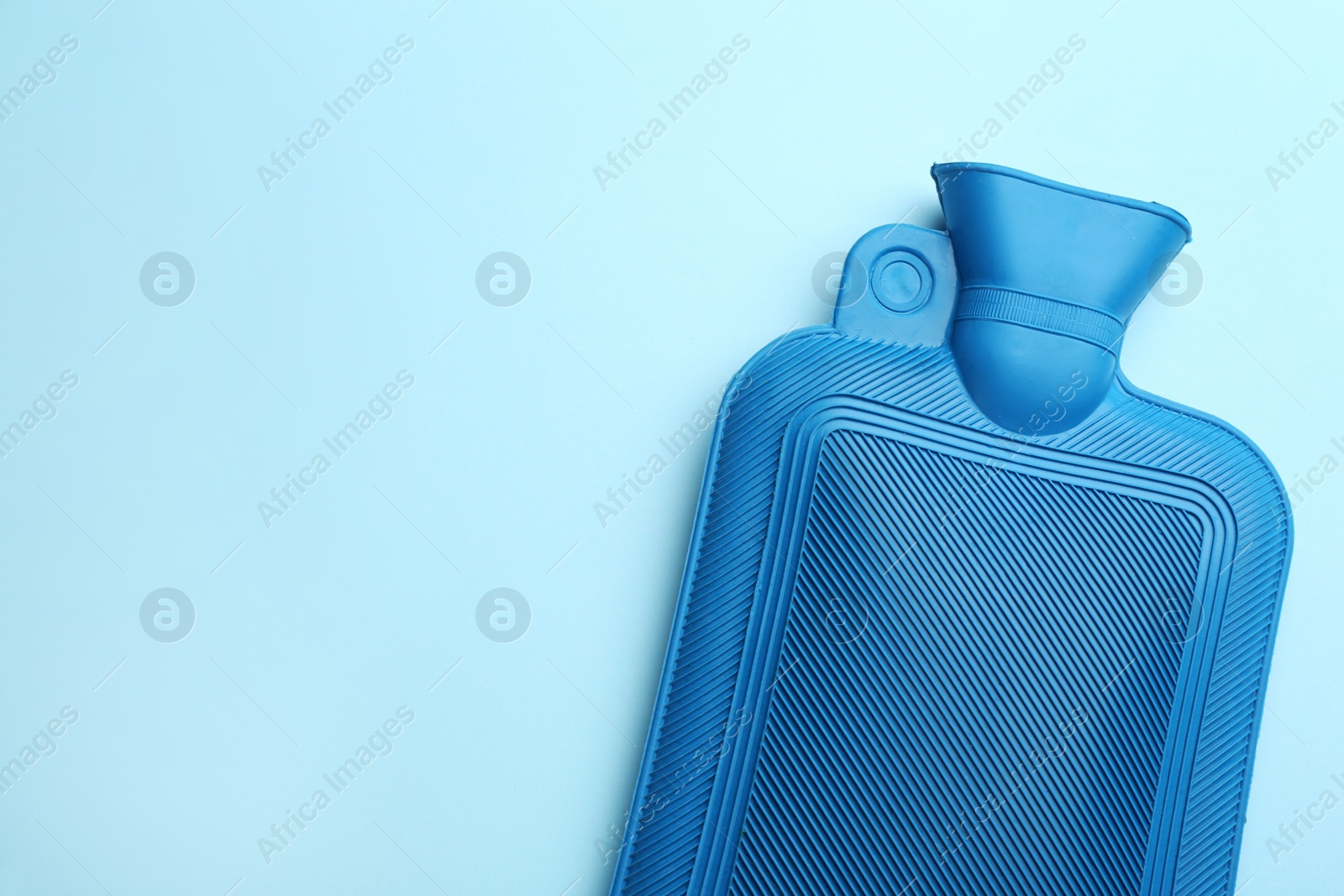 Rubber hot water bottle on light blue background, top view. Space for text Photo of Rubber hot water bottle on light blue background, top view. Space for text
