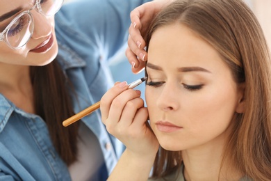 Professional visage artist applying makeup on woman's face in salon Photo of Professional visage artist applying makeup on woman's face in salon