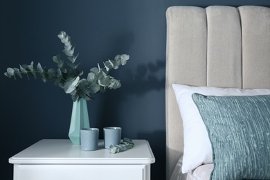 Beautiful eucalyptus branches and candles on nightstand in bedroom. Interior element Photo of Beautiful eucalyptus branches and candles on nightstand in bedroom. Interior element