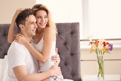 Photo of Happy young couple hugging on bed at home