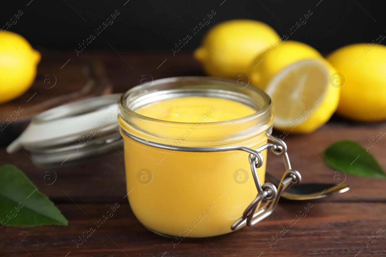 Delicious lemon curd in glass jar on wooden table Photo of Delicious lemon curd in glass jar on wooden table