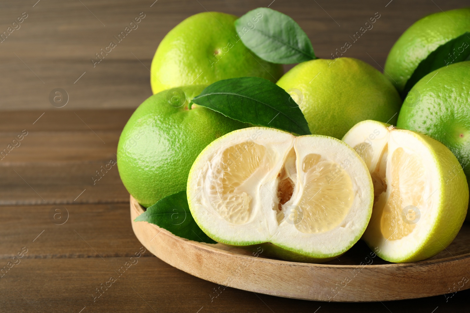 Whole and cut sweetie fruits on wooden table Photo of Whole and cut sweetie fruits on wooden table