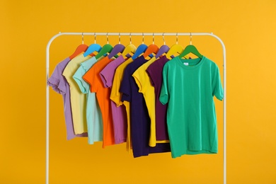 Rack with stylish children clothes on yellow background Photo of Rack with stylish children clothes on yellow background