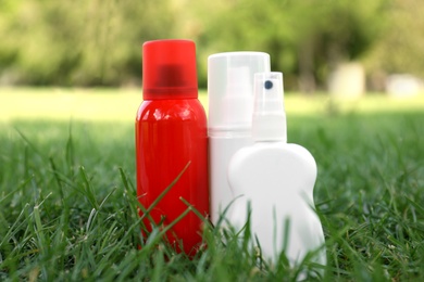 Bottles of insect repellent on green grass Photo of Bottles of insect repellent on green grass