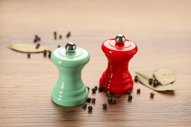 Salt and pepper shakers with bay leaves on wooden table, closeup. Spice mill Photo of Salt and pepper shakers with bay leaves on wooden table, closeup. Spice mill