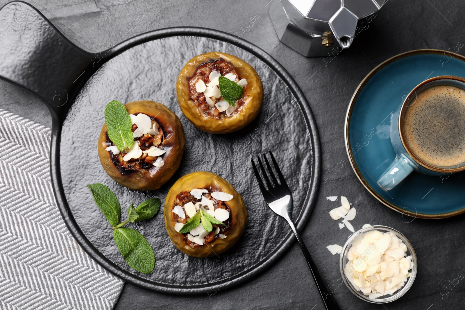 Delicious baked apples with nuts and mint served on black table, flat lay Photo of Delicious baked apples with nuts and mint served on black table, flat lay