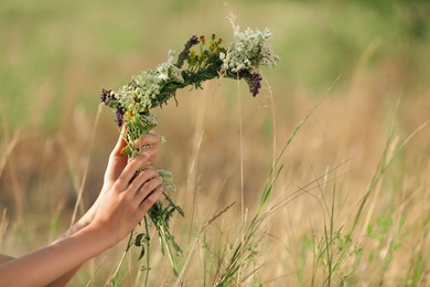 Little girl making wreath of beautiful flowers in field on sunny day, closeup Photo of Little girl making wreath of beautiful flowers in field on sunny day, closeup