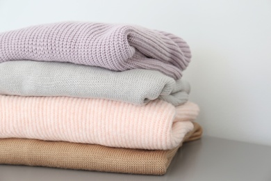 Stack of folded warm knitted sweaters on grey table, closeup Photo of Stack of folded warm knitted sweaters on grey table, closeup