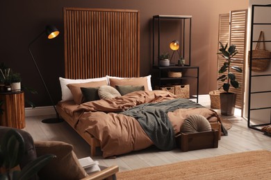 Stylish room interior with large bed near brown wall Photo of Stylish room interior with large bed near brown wall