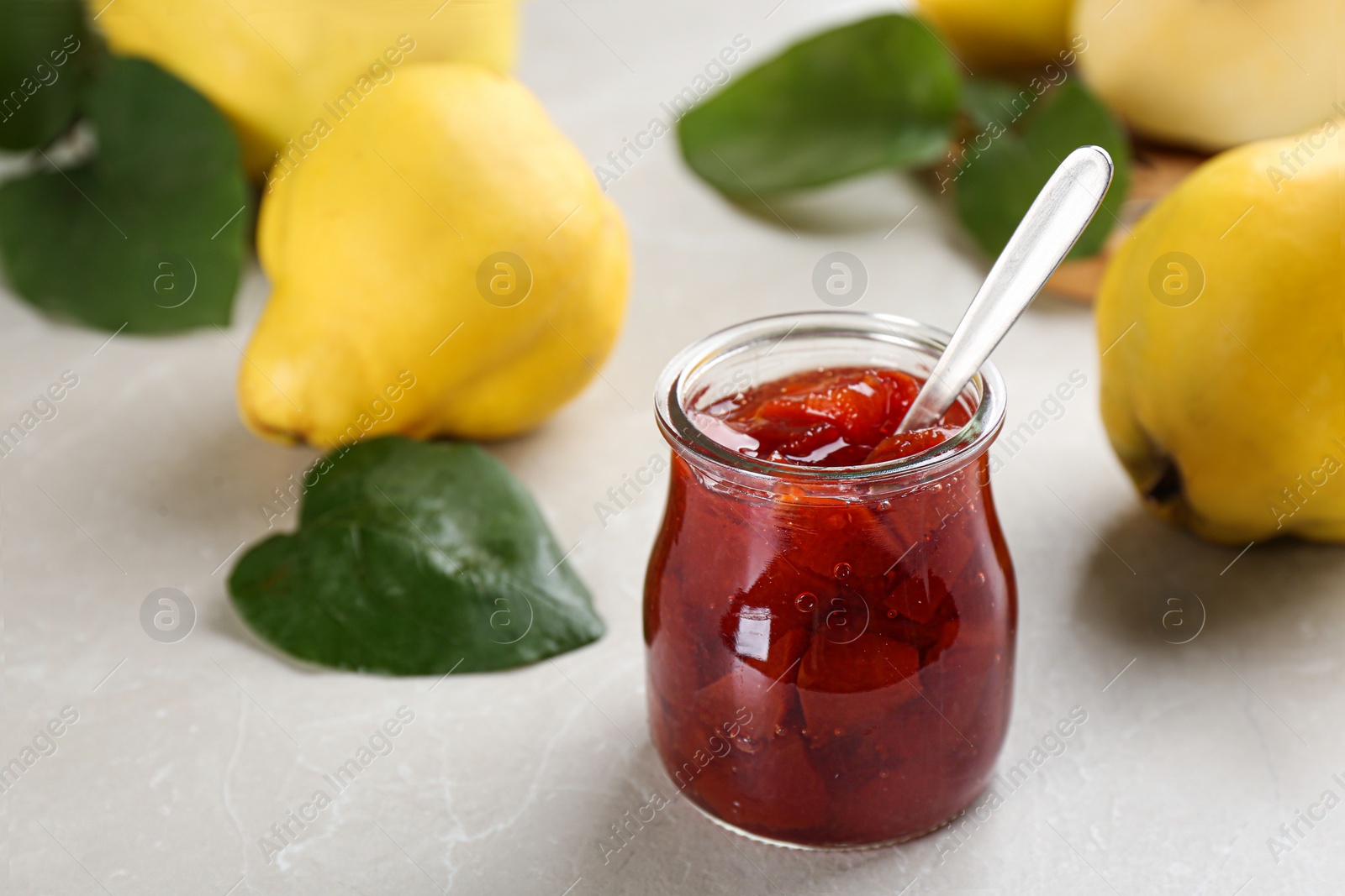 Photo of Delicious quince jam on light grey marble table, closeup