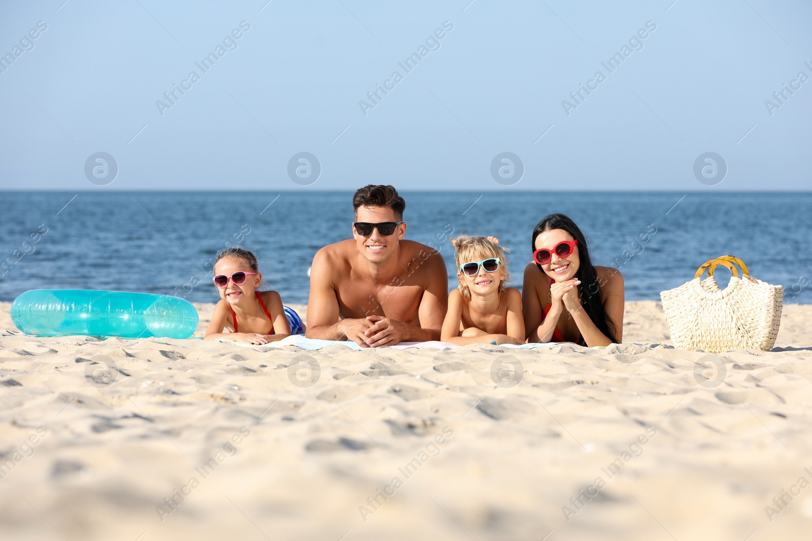 Photo of Happy family on sandy beach near sea. Summer holidays