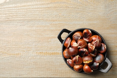 Tasty roasted edible chestnuts on wooden table, top view. Space for text Photo of Tasty roasted edible chestnuts on wooden table, top view. Space for text