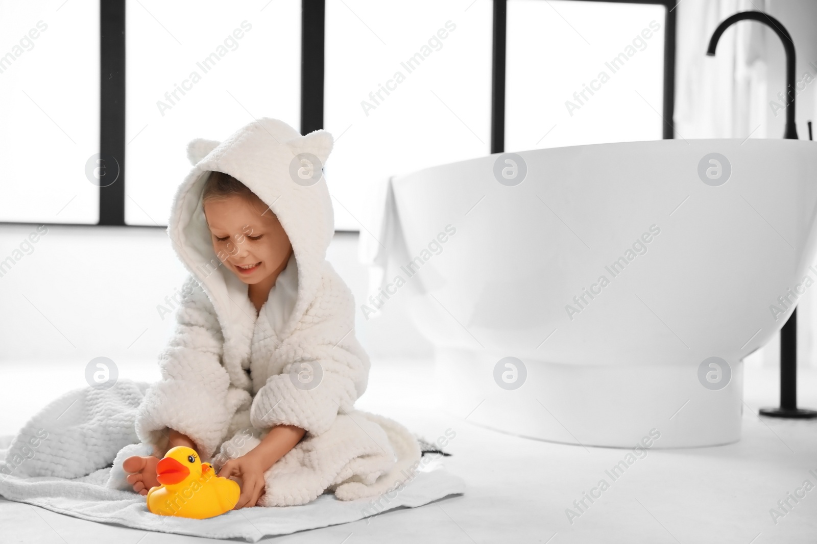 Photo of Cute little girl near tub in bathroom. Space for text