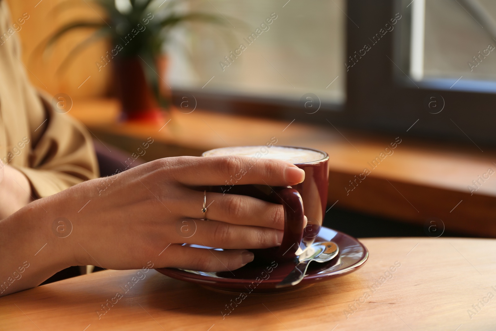 Photo of Woman with aromatic coffee at table in cafe, closeup