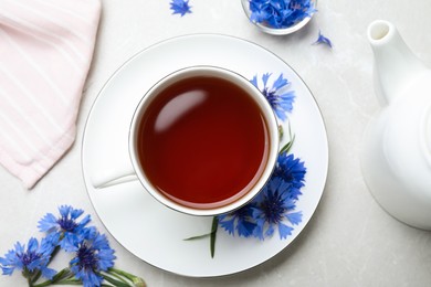 Composition with tea and cornflowers on light table, flat lay Photo of Composition with tea and cornflowers on light table, flat lay
