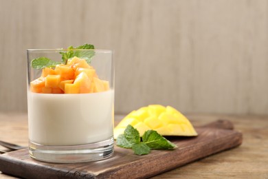 Delicious panna cotta with mango on wooden table. Space for text Photo of Delicious panna cotta with mango on wooden table. Space for text