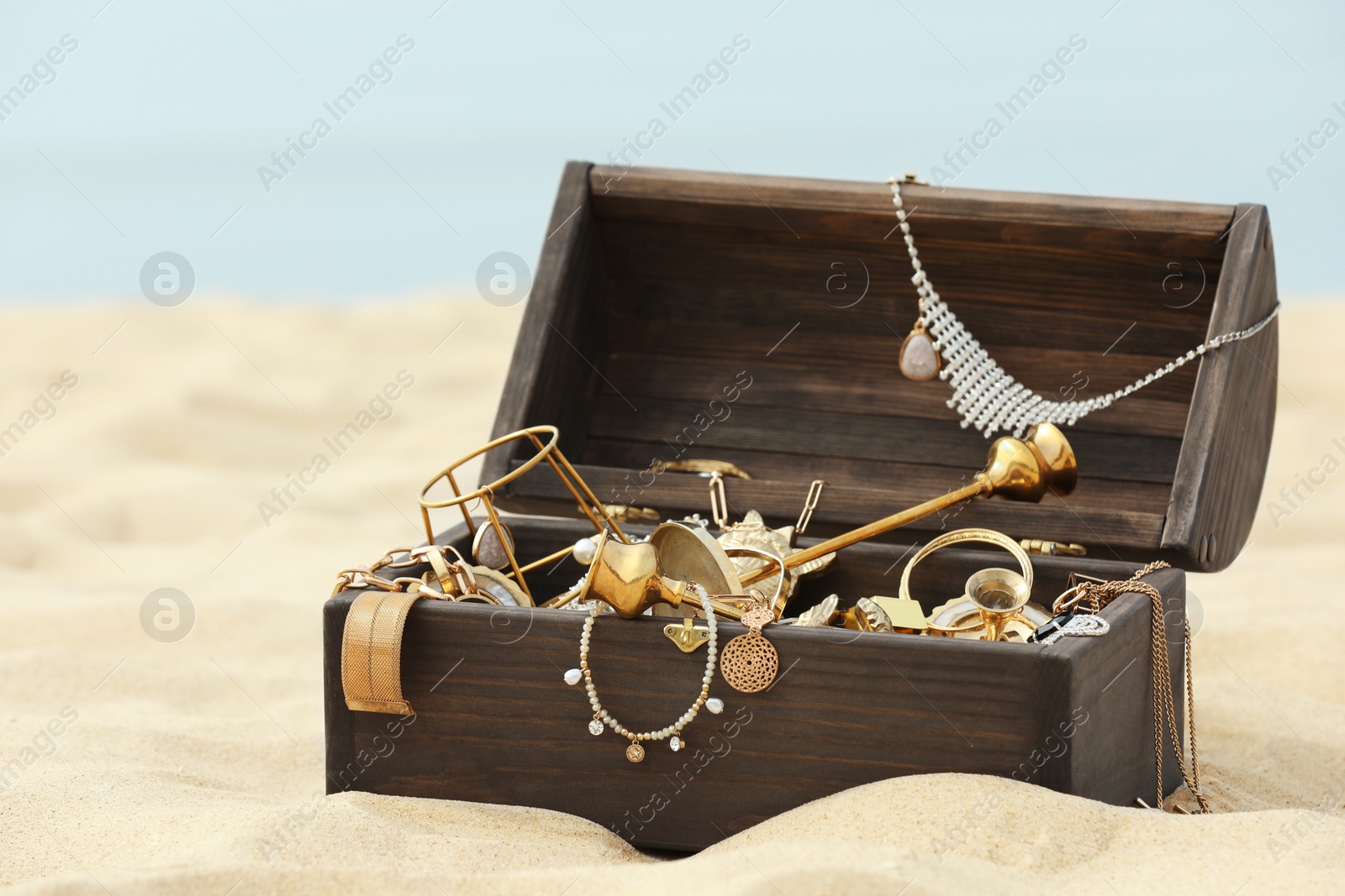 Open wooden treasure chest on sandy beach Photo of Open wooden treasure chest on sandy beach