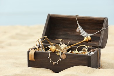 Open wooden treasure chest on sandy beach Photo of Open wooden treasure chest on sandy beach