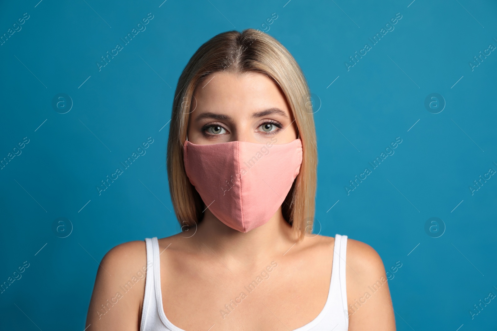 Young woman in protective face mask on blue background Photo of Young woman in protective face mask on blue background