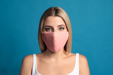 Young woman in protective face mask on blue background Photo of Young woman in protective face mask on blue background