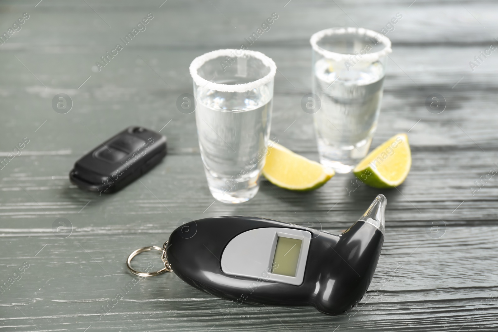 Modern breathalyzer, alcohol and car key on grey wooden background Photo of Modern breathalyzer, alcohol and car key on grey wooden background
