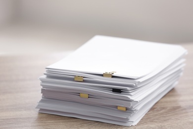 Stack of blank paper with binder clips on wooden table Photo of Stack of blank paper with binder clips on wooden table