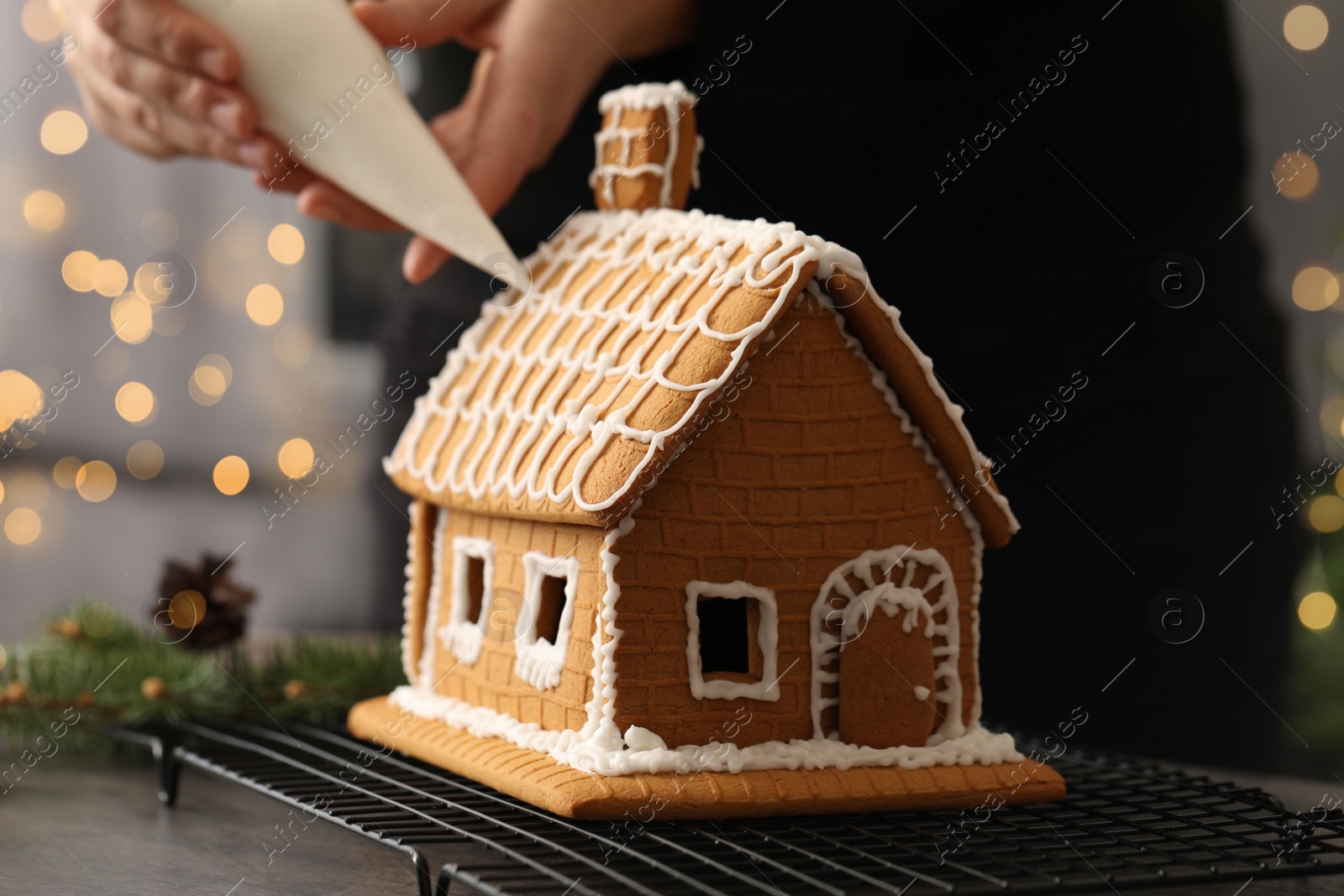 Woman decorating gingerbread house with icing at table, closeup Photo of Woman decorating gingerbread house with icing at table, closeup
