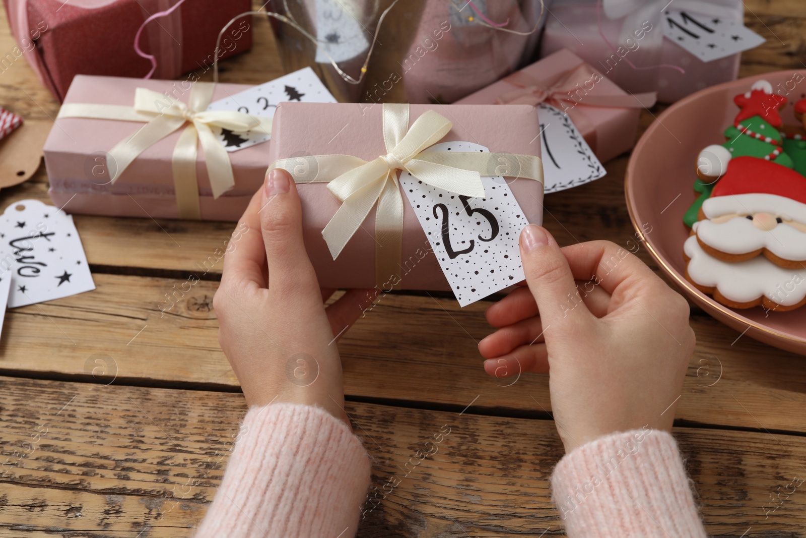 Woman making advent calendar at wooden table, closeup Photo of Woman making advent calendar at wooden table, closeup