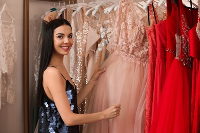 Woman choosing dress in rental clothing salon Photo of Woman choosing dress in rental clothing salon