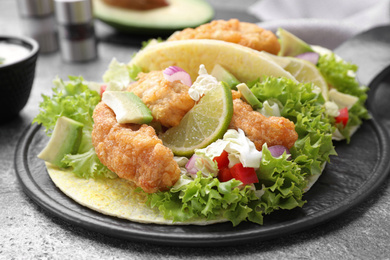 Photo of Delicious fish tacos served on grey table, closeup