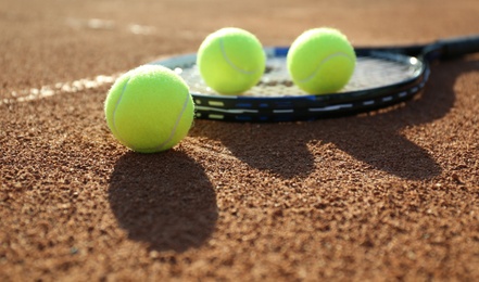 Tennis balls and racket on clay court Photo of Tennis balls and racket on clay court