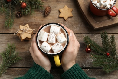 Woman with cup of delicious marshmallow cocoa at wooden table, top view Photo of Woman with cup of delicious marshmallow cocoa at wooden table, top view