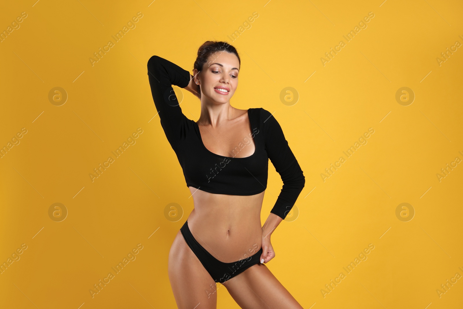 Beautiful woman in black sexy panties on yellow background Photo of Beautiful woman in black sexy panties on yellow background
