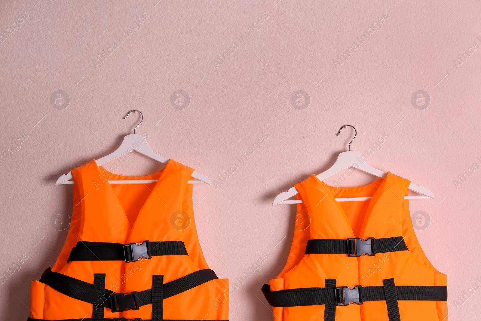 Orange life jackets on pink background. Personal flotation device Photo of Orange life jackets on pink background. Personal flotation device