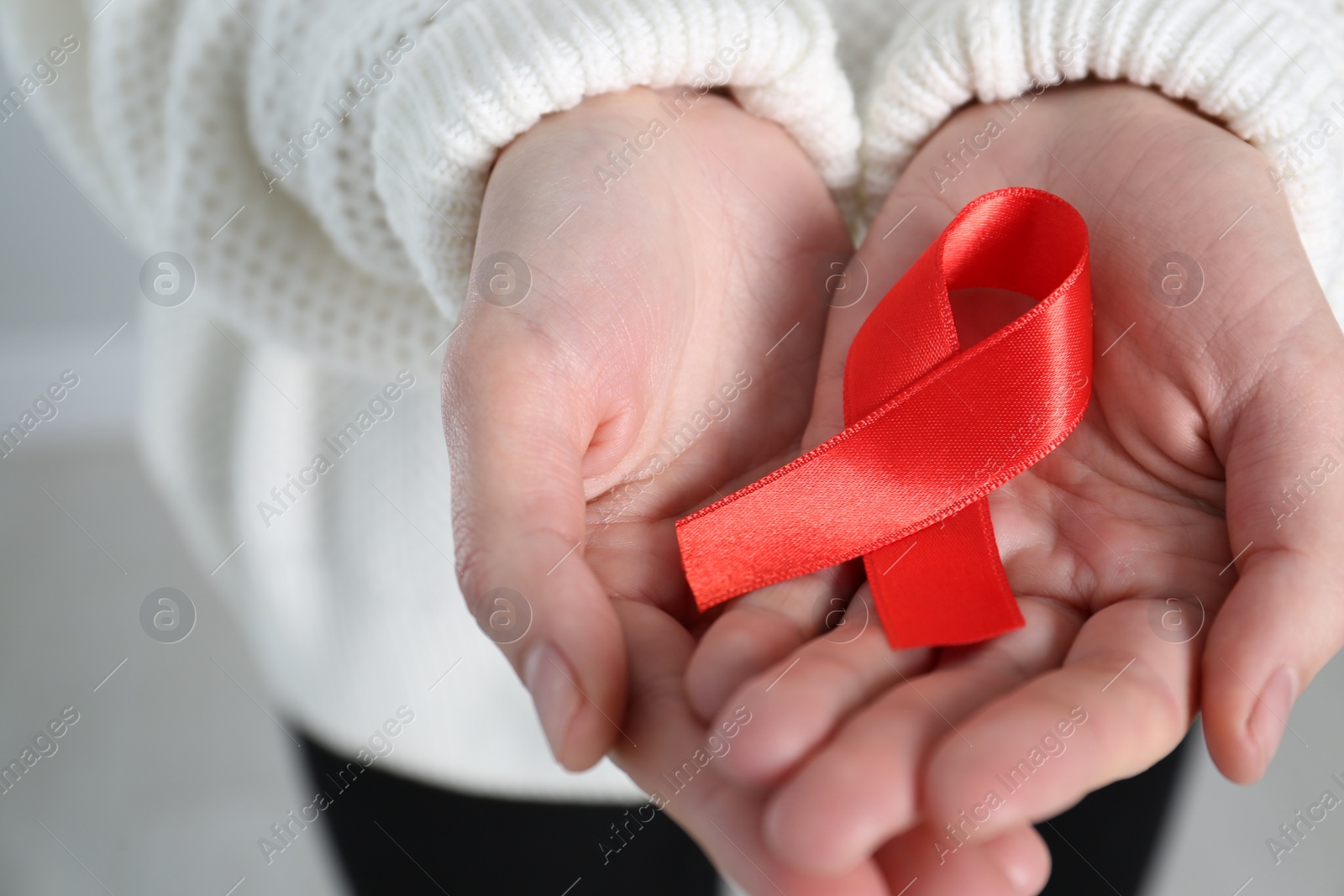 Woman holding red awareness ribbon, closeup. World AIDS disease day Photo of Woman holding red awareness ribbon, closeup. World AIDS disease day