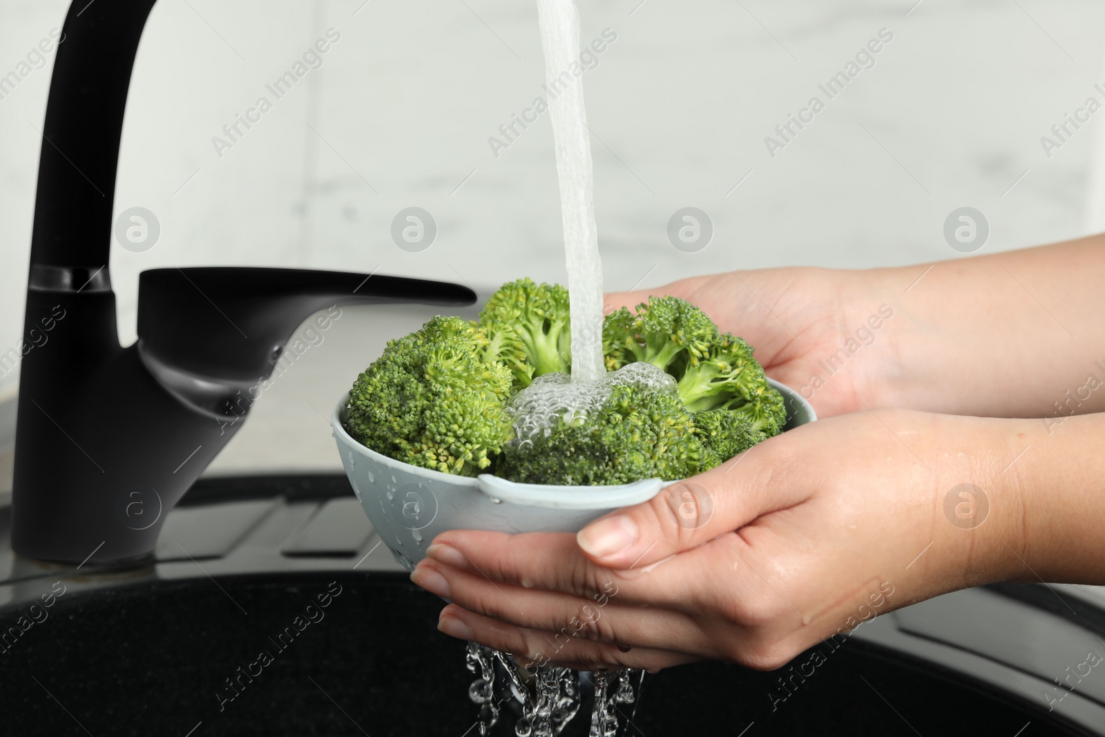Woman washing fresh green broccoli in kitchen sink, closeup Photo of Woman washing fresh green broccoli in kitchen sink, closeup