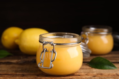 Delicious lemon curd in glass jar on wooden table Photo of Delicious lemon curd in glass jar on wooden table