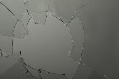 Closeup view of broken glass with cracks on grey background Photo of Closeup view of broken glass with cracks on grey background
