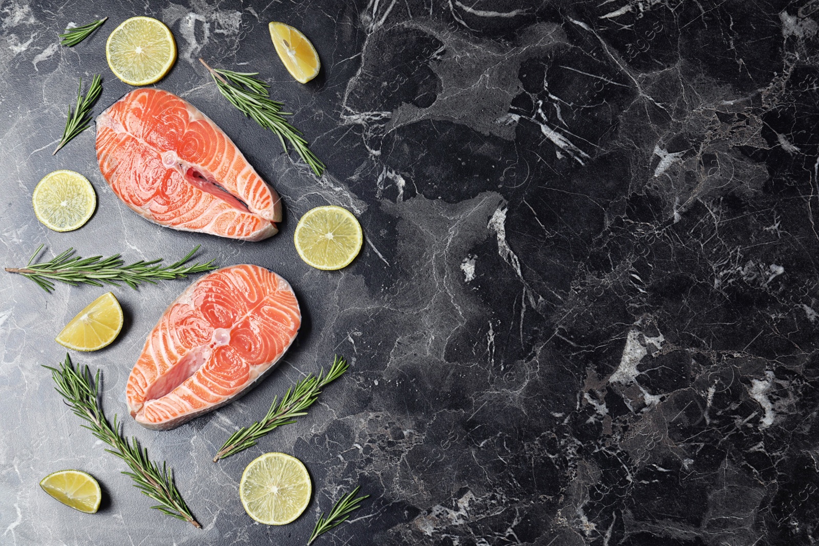 Flat lay composition with fresh raw salmon and rosemary on black marble table, space for text. Fish delicacy Photo of Flat lay composition with fresh raw salmon and rosemary on black marble table, space for text. Fish delicacy