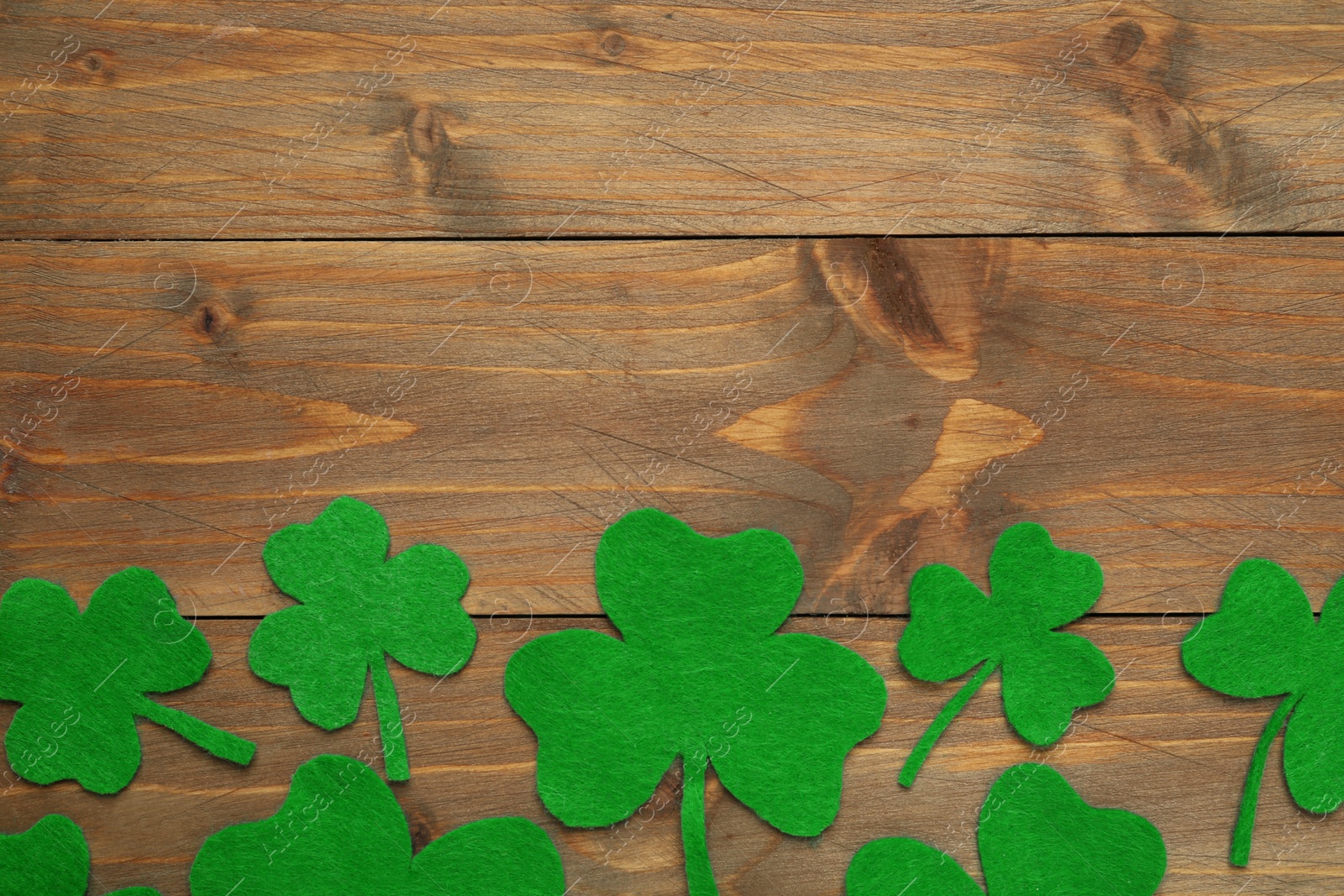 Decorative clover leaves on wooden background, flat lay with space for text. St. Patrick's Day celebration Photo of Decorative clover leaves on wooden background, flat lay with space for text. St. Patrick's Day celebration
