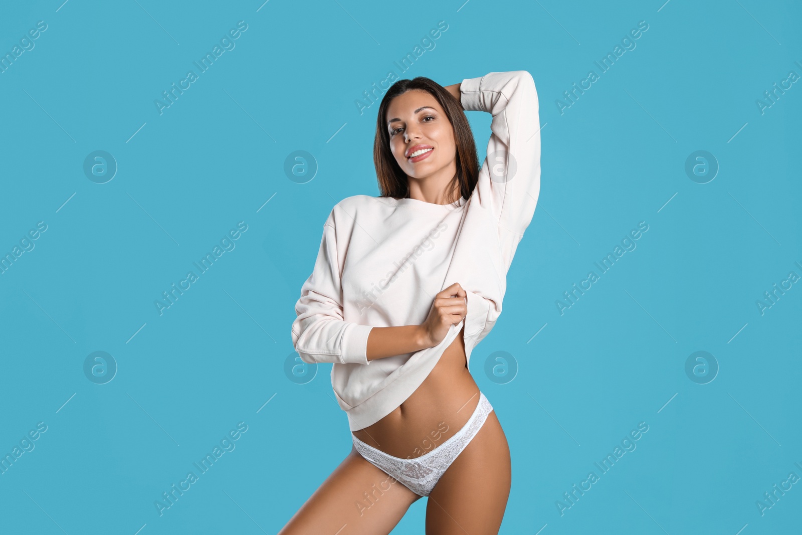 Beautiful woman in white sexy panties and sweater on light blue background Photo of Beautiful woman in white sexy panties and sweater on light blue background