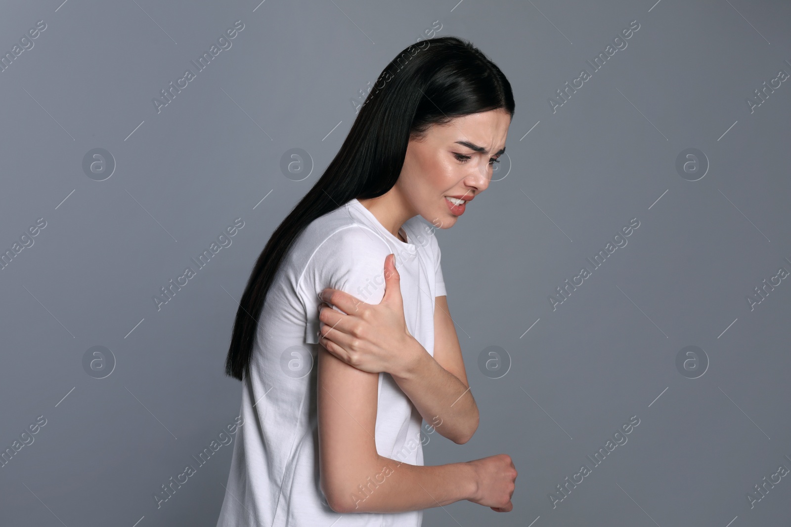 Woman suffering from shoulder pain on grey background Photo of Woman suffering from shoulder pain on grey background