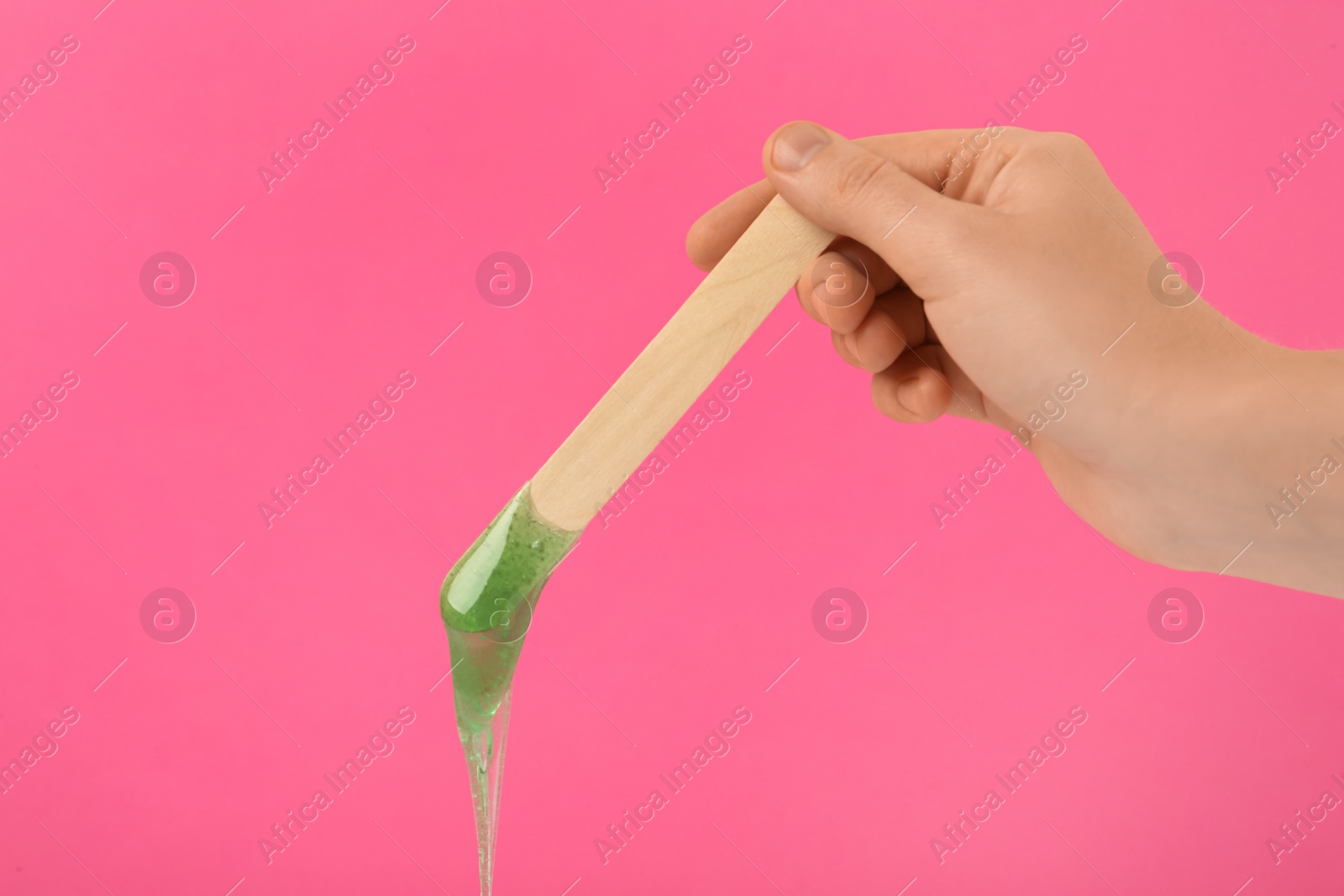 Woman holding spatula with hot depilatory wax on pink background, closeup Photo of Woman holding spatula with hot depilatory wax on pink background, closeup