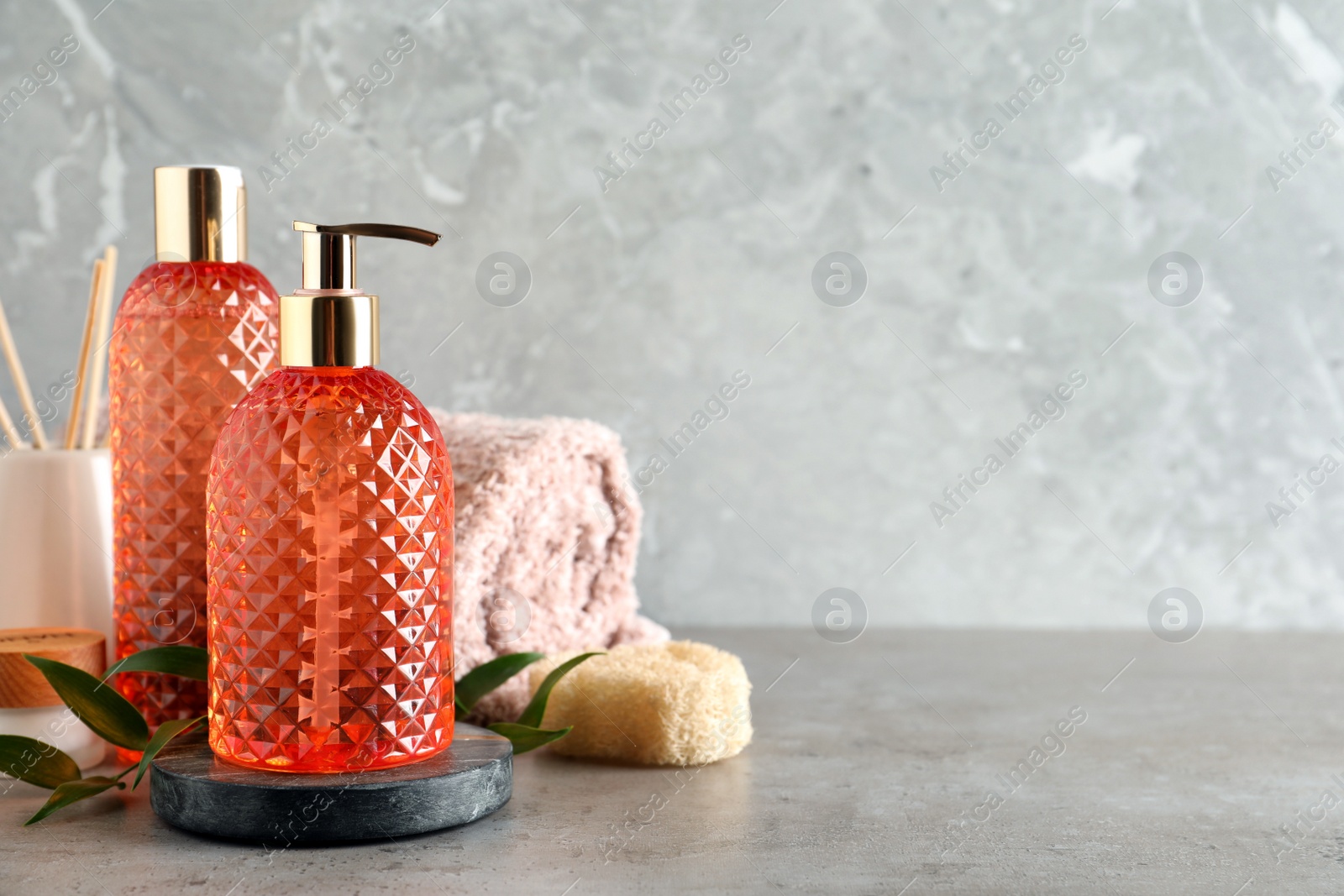 Stylish dispenser with liquid soap and other bathroom amenities on grey table, space for text Photo of Stylish dispenser with liquid soap and other bathroom amenities on grey table, space for text