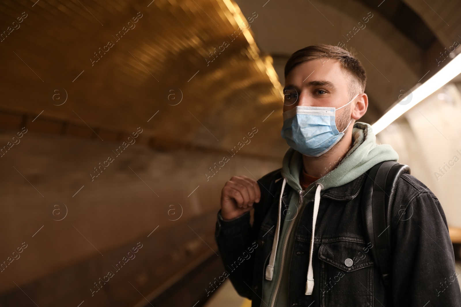 Young man in protective mask at subway station, space for text. Public transport Photo of Young man in protective mask at subway station, space for text. Public transport