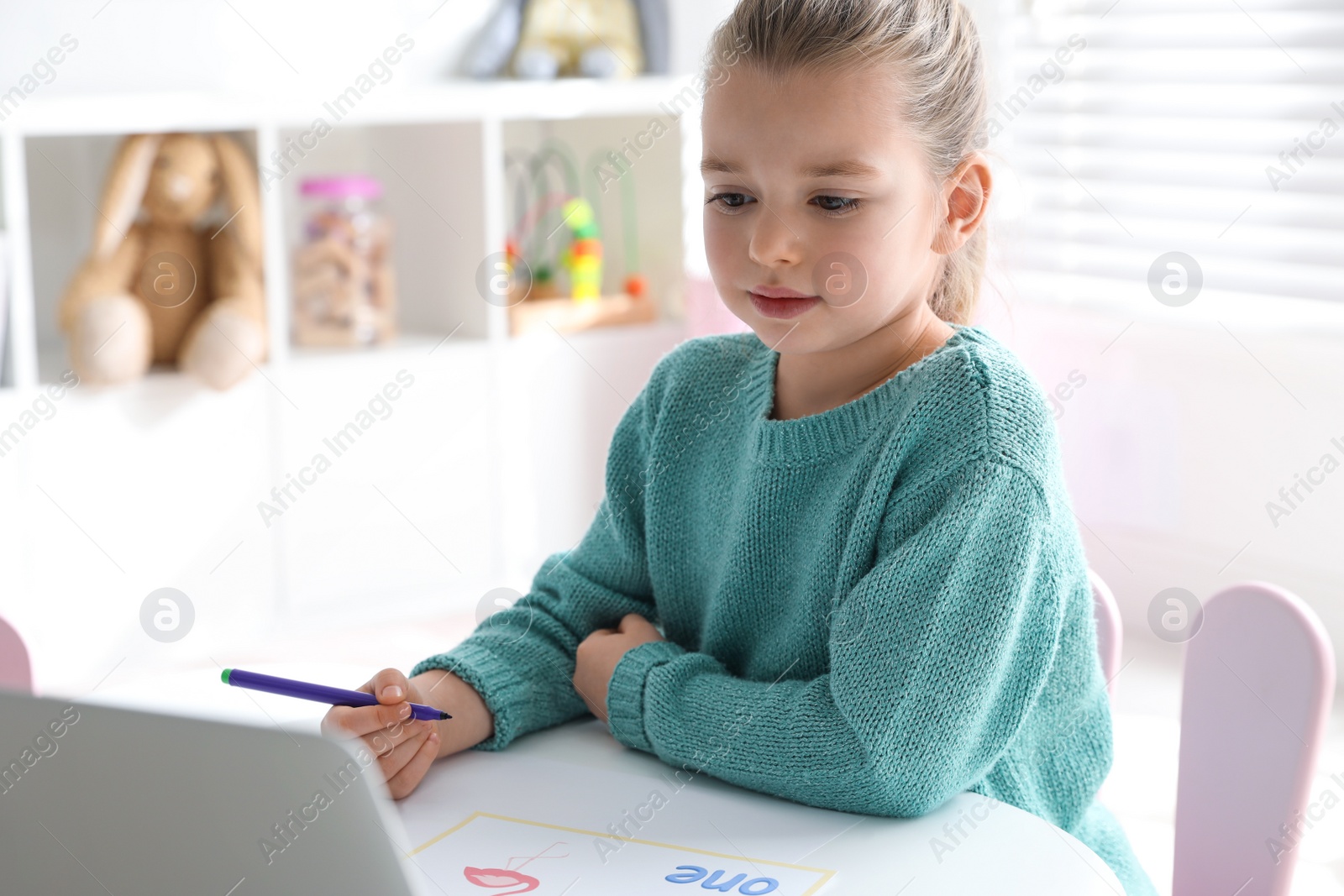 Little girl learning English indoors at online lesson Photo of Little girl learning English indoors at online lesson